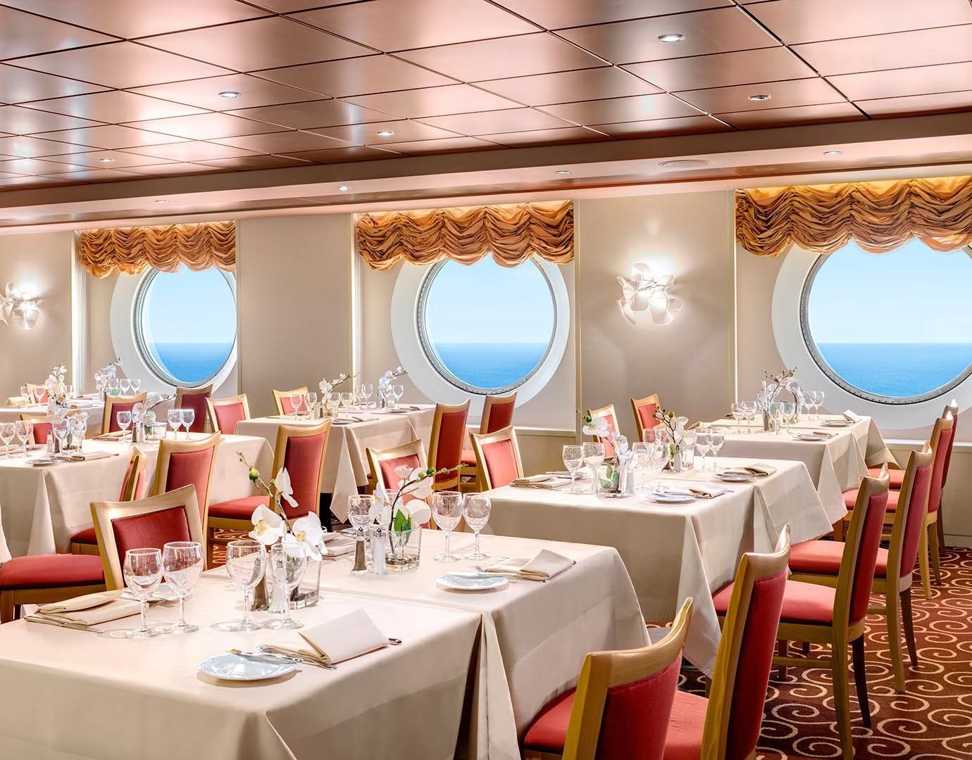 Restaurant à bord du MSC Armonia avec tables dressées et hublots sur la mer