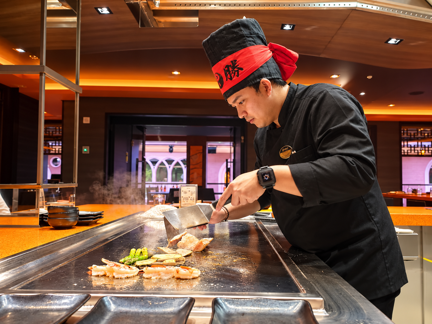 Chef teppanyaki en pleine cuisson sur la plaque